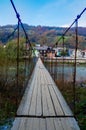 Old suspension bridge across the river in a mountain village Royalty Free Stock Photo