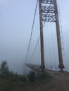 Old suspension bridge fog view. Altai village bridge. Early misty morning Royalty Free Stock Photo