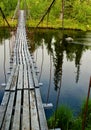 Old suspension walk bridge across river in the forest