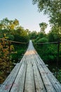 Old suspension wooden bridge across the river in the forest. Summer evening Royalty Free Stock Photo