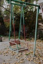 Old swing on a children's playground made of metal structure. Outdated unsafe game elements. Soviet courtyard in Royalty Free Stock Photo