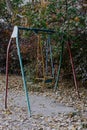 Old swing on a children's playground made of metal structure. Soviet courtyard in autumn foliage. Outdated unsafe Royalty Free Stock Photo