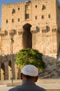 An old Syrian man sits in front of the entrance to the Citadel of Aleppo, Syria. Royalty Free Stock Photo