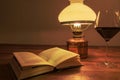 Old table lamp with book and glass of red wine on old wooden table