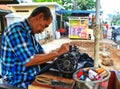 An old tailor sewing pants on the side of the road on a Sunday morning in Ciledug, near Jakarta Indonesia