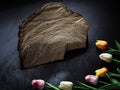 wooden base on black background and decorated fake tulips for product stand. Royalty Free Stock Photo