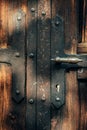 Old tared wooden door with metal reinforcements and brass handle Royalty Free Stock Photo