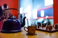 Old teapot on the table. Near the glass and chess Royalty Free Stock Photo