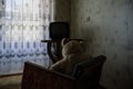 Old Teddy bear sitting on chair and watching TV