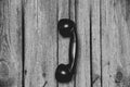 Old telephone black tube hanging on the wall on a cable on a wooden background close-up, old retro telephone Royalty Free Stock Photo