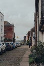 Old terraced house on a cobbled street in Rye, UK, cars parked opposite, people walk on the background Royalty Free Stock Photo