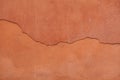 Old terracotta painted stucco wall with cracked plaster. Background texture