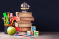 Old textbooks and school supplies are on the rustic wooden table on a background of black chalk board. Royalty Free Stock Photo