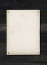 Old textured paper sheet nailed on a black wood table Royalty Free Stock Photo
