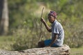 Old Tharu man sitting on a log Royalty Free Stock Photo