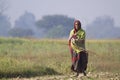 Old tharu woman walking in fields in Nepal