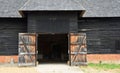 Old thatched barn with large doors open.