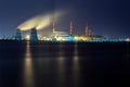 Old thermal 450 megawatt power plant at night with artificial lake on foreground