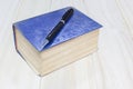 Old thick book blue cover and pen on wooden background Royalty Free Stock Photo