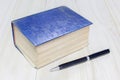 Old thick book blue cover and pen on wooden background Royalty Free Stock Photo