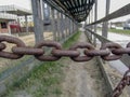 Old thick metal chain with heavy rust. Stretched links rusty chain on outdoor street. Closed passage. Closeup. Royalty Free Stock Photo