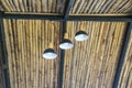 Old three white electric light lamps hanging on ceiling bamboo roof interior on background Royalty Free Stock Photo