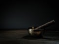 Old Tibetan singing bowl on wooden base, black background. Music therapy