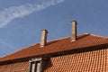 Old tiled roof with chimneys and window against blue sky Royalty Free Stock Photo