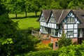 Tudor house surrounded by trees and shrubs.