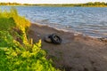 Old tires at the edge of a lake. Lake pollution. Royalty Free Stock Photo