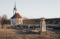 Old Tombstones in public cemetery in European village with chapel on background on sunset. Blank tombstone and graves in ancient