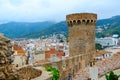 Old tower and stone walls against background of resort town of Tossa de Mar and mountains, Spain Royalty Free Stock Photo