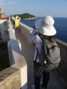 tourists walking along the wall of Dubrovnik old town with brightly coloured sun hats