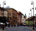 Old town square buildings lit by the sun in a row, people in the market square