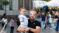 Bearded man with a child on his hands watches and rejoices at the gigantic soap bubbles, Old Town Square, Riga, Latvia