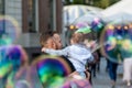 Bearded man with a child on his hands watches and rejoices at the gigantic soap bubbles, Old Town Square, Riga, Latvia