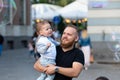 Bearded man with a child on his hands watches and rejoices at the gigantic soap bubbles, Old Town Square, Riga, Latvia