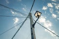Old town street lamp with tangled power cables under a blue sunny sky with scattered clouds in castilla la mancha, spain