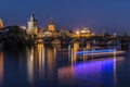 Charles Bridge and Old Town Tower at night with reflections on the Vltava and light from the boat Royalty Free Stock Photo