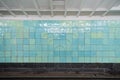 Old track wall at the metro station, lined with shabby turquoise glazed ceramic tiles