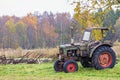 Old tractor with old agricultural tools on a meadow in an autumn landscape Royalty Free Stock Photo