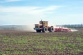 An old tractor is dragging a modern aggregate for tillage leveling the field surface Royalty Free Stock Photo