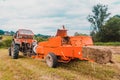 Old tractor in the field, forage harvesting for the winter, press and hay, pressing dry grass Royalty Free Stock Photo