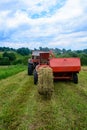 Old tractor in the field, forage harvesting for the winter, press and hay, pressing dry grass Royalty Free Stock Photo