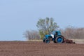 An old tractor in the field plows the land. Spring landscape of a countryside, a farm Royalty Free Stock Photo