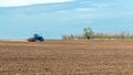 An old tractor in the field plows the land. Spring landscape of a countryside, a farm Royalty Free Stock Photo