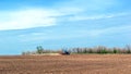 An old tractor in the field plows the land. Spring landscape of a countryside, a farm Royalty Free Stock Photo