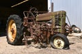 Old tractor with flat tire and field cultivator