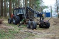 Old tractor in the forest to transport timber in the forest among the pine trees. The concept of cutting down trees Royalty Free Stock Photo