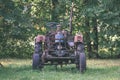 old tractor with rubber tires in green countryside yard in green summer - vintage retro film look Royalty Free Stock Photo